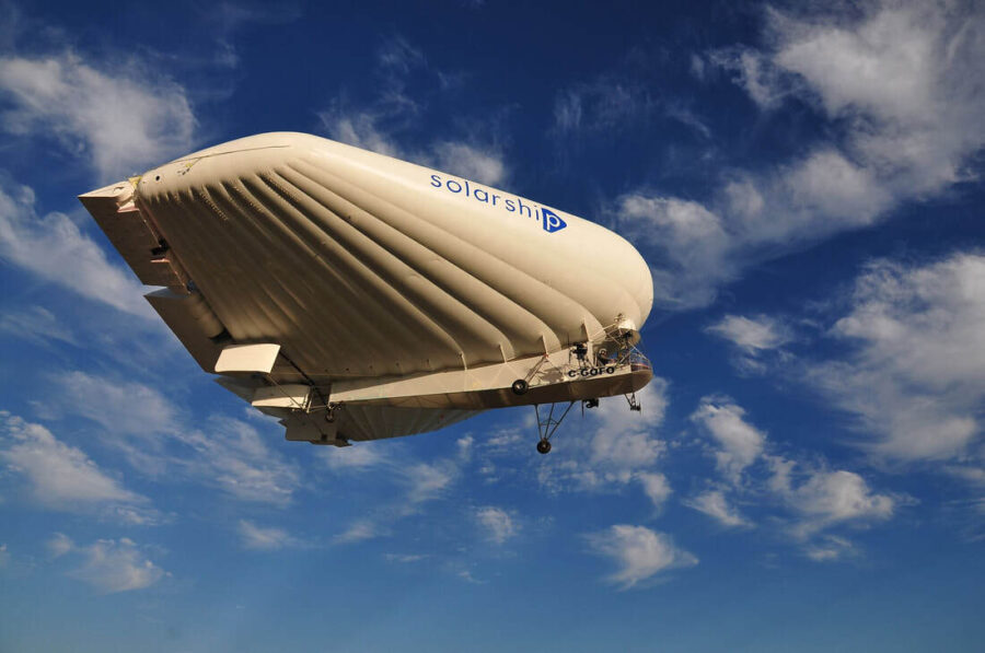 Solar ship inflatable plane drifts across a blue sky, white wispy clouds high above.