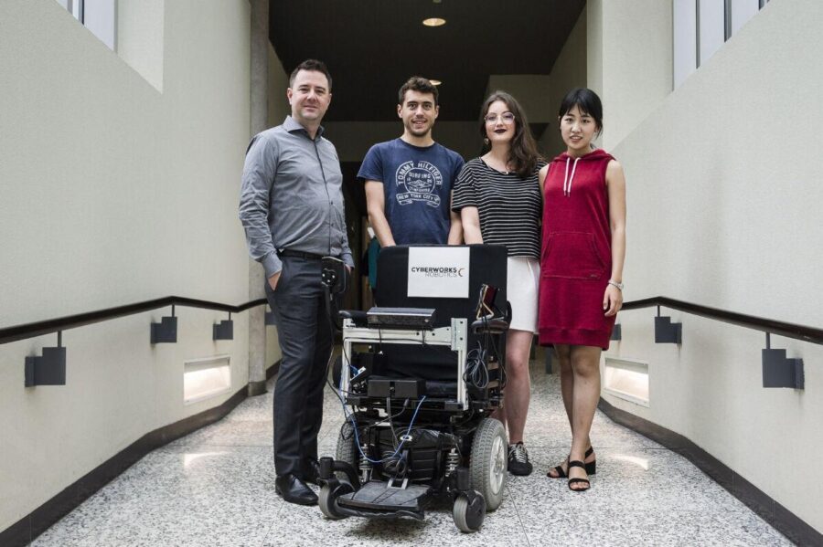 Behind their autonomous wheelchair invention, Jonathan Kelly, U of T assistant professor, poses with students Rodolphe Perrin, Mathilde Hede and Xinyi Li