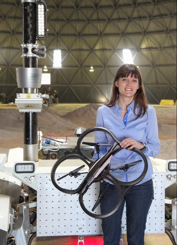 Professor Angela Schoellig holds a small four-prop drone.