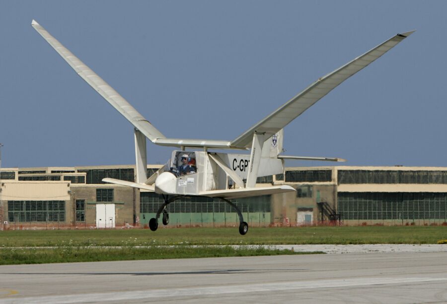 An ornithopter flies low above the ground, its wings in mid-flap.