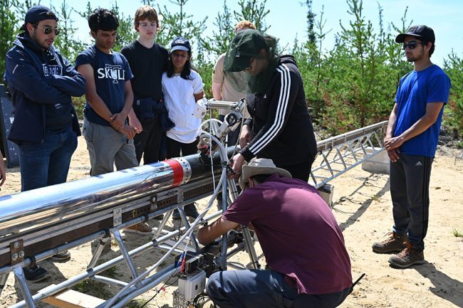 Members of the University of Toronto Aerospace Team (UTAT) Rocketry Division make adjustments to Defiance, their record-breaking experimental hybrid rocket, at the launch site near Cochrane, Ontario in early August 2022