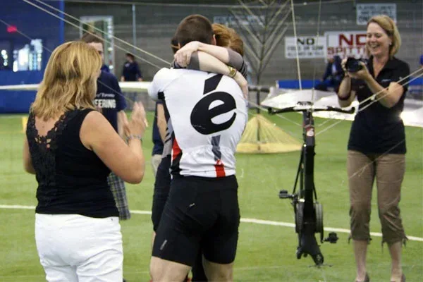 Todd Reichert, UTIAS grad, celebrates the successful flight of a human-powered helicopter, embracing a woman before onlookers.