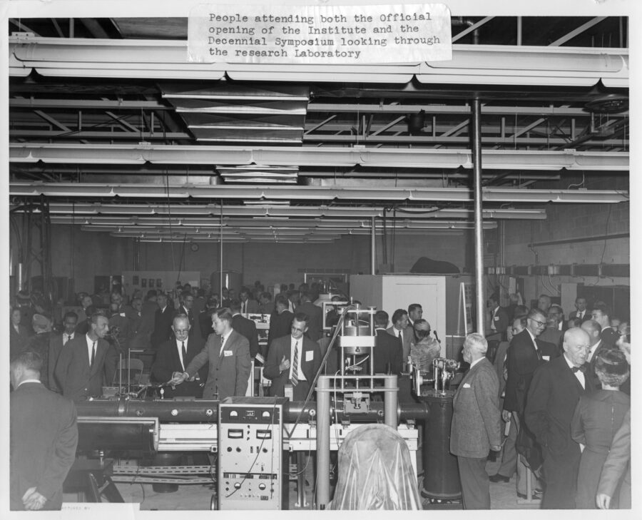 A large group of people attending the official opening of the Institute of Aerophysics look through a research laboratory.