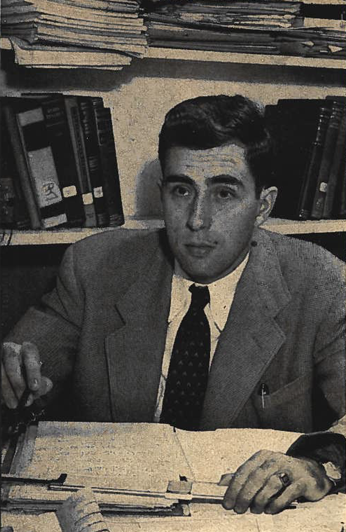 Gerald Bull, young engineer, with his notebook and slide rule, a wall of books and papers behind him.