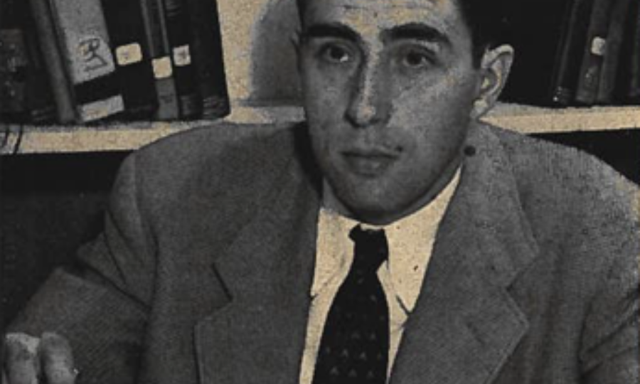 Gerald Bull, young engineer, with his notebook and slide rule, a wall of books and papers behind him.